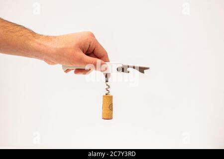 Mano di un uomo che tiene un cavatappi con un sughero tappo isolato su fondo bianco Foto Stock