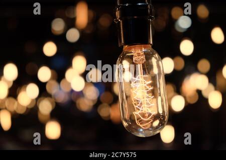 primo piano una lampadina elettrica dorata brillante, bella bokeh al buio Foto Stock