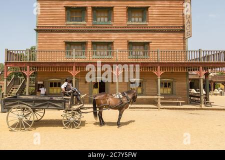 Cowboy seduto in una carrozza accanto a un edificio in legno a Western Town, Spagna Foto Stock