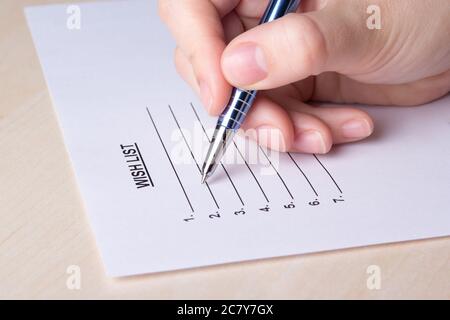 mano femminile che scrive la sua lista dei desideri con la penna Foto Stock