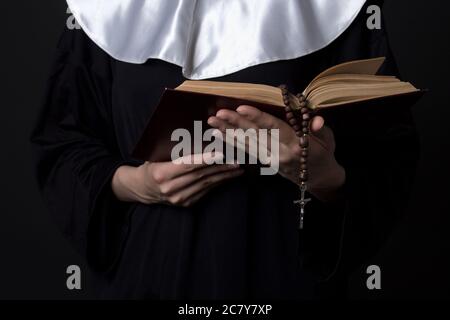 Nun mani tenendo la bibbia prenota su sfondo grigio Foto Stock