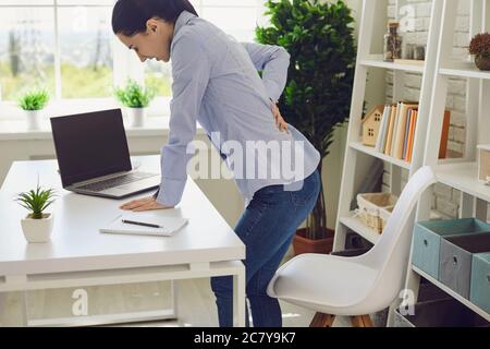 Mal di schiena. Donna che soffre di mal di schiena sul posto di lavoro. Foto Stock