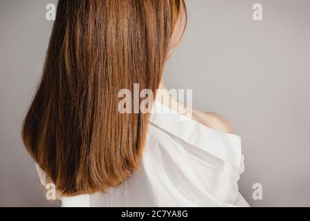Vista posteriore di una giovane donna in camicia bianca con un'udito lungo e brillante. Foto Stock