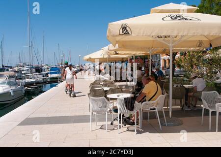 Izola, Slovenia - 16 luglio 2020: Ristorante nel porto di Marina Izola-valobran. Persone in vacanza in un caffè a Izola, Slovenia. Foto Stock