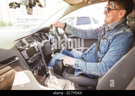 Uomo quadriplegico seduto sul sedile della sua auto di controllo personalizzata. Sta sorridendo per la fotocamera. Foto Stock