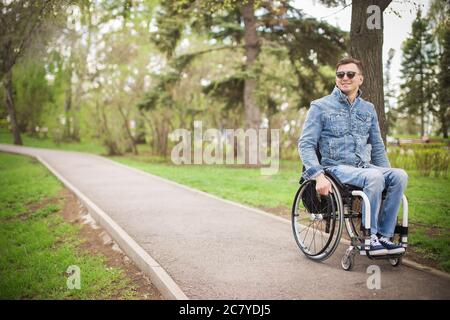 Invalid uomo seduto su una sedia a rotelle e di godere di una passeggiata all'aperto Foto Stock