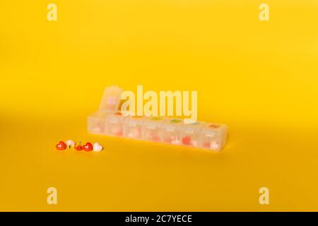 Primo piano di colorati perni a forma di cuore in un contenitore di plastica su una superficie gialla Foto Stock