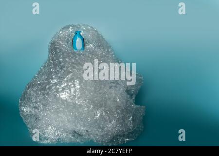 Primo piano di un giocattolo blu dei pinguini su una plastica borsa con sfondo blu Foto Stock