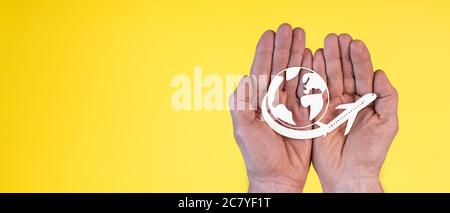 Concetto di assicurazione di viaggio con aereo di carta che vola in tutto il mondo in mani su sfondo giallo Foto Stock