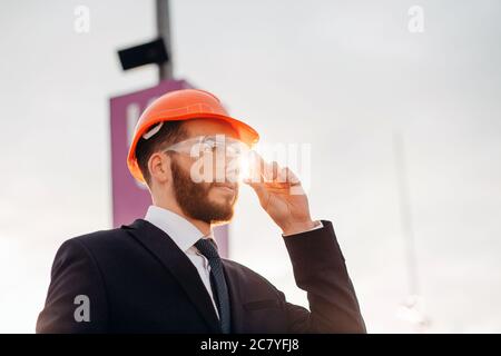 Bel uomo barbuto lavoratore con barba e baffi sul viso grave nella costruzione di casco o elmetto di builder o ingegnere professionale Foto Stock
