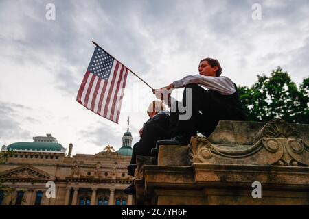 Indianapolis, Stati Uniti. 19 luglio 2020. Un protester tiene una bandiera americana mentre ascolta i diffusori durante il We Will Not Aconda anti maschera rally.People protesta contro sia il sindaco di Indianapolis Joe Hogsett's maschera ordine e il governatore dell'Indiana Eric Holcomb estensione dello stato di chiusura. Il Dipartimento della Salute degli Stati Uniti ha registrato un totale di 3,898,550 infezioni, 143,289 decessi e 1,802,338 rinvenuti dall'inizio dell'epidemia di Coronavirus (Covid-19). Credit: SOPA Images Limited/Alamy Live News Foto Stock