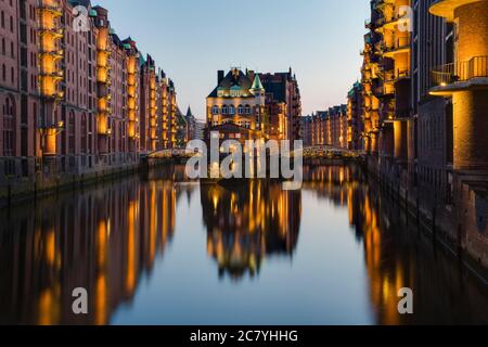 Speicherstadt illuminato ad Amburgo la sera all'ora blu con riflesso in acqua (esposizione lunga) Foto Stock