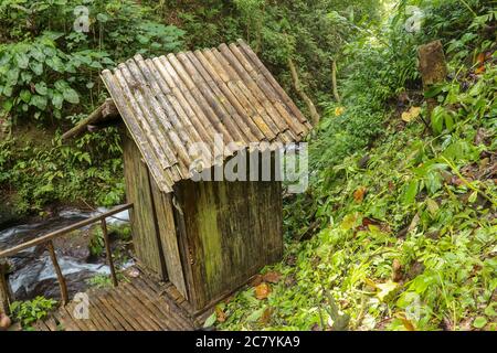 Spogliatoio costruito di tronchi di bambù da un fiume in una foresta tropicale pioggia. Piccola casa a Spray Waterfall su Bali Island alta in montagna. Valle Foto Stock