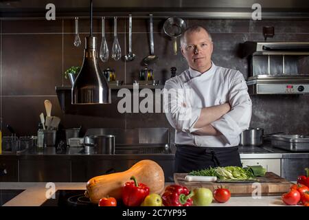 Ritratto di un maschio sorridente chef con il cibo cotto in piedi in cucina Foto Stock