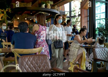 Personale e clienti che indossano la maschera Coronavirus in un luogo affollato. Boutique cafe e caffetteria in stile vintage, Tailandia, Sud-Est Asiatico. Foto Stock
