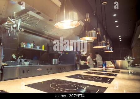Interno cucina ristorante: Bancone bar in pietra naturale, recinzioni fuori cucina aperta e salone per visitatori con tavoli e sedie. Nel backg Foto Stock