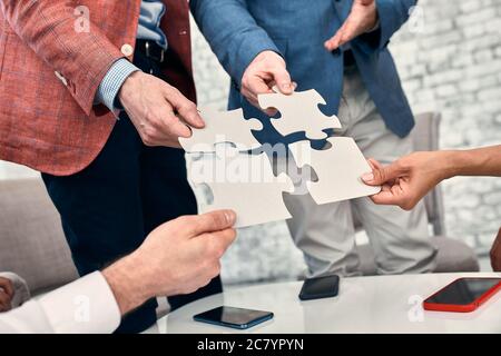 Immagine ritagliata di imprenditori unire i pezzi del puzzle in office Foto Stock