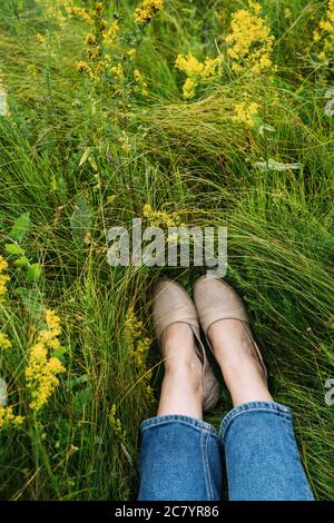 I piedi della donna giacciono sull'erba. Riposo estivo. Vista dall'alto. Foto Stock