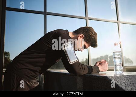 Giovane attraente uomo sportivo stanco che riposa dopo la corsa all'aperto Foto Stock