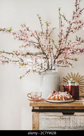 Torta di mandorle di rose e tè sotto rami fiorenti di mandorle Foto Stock