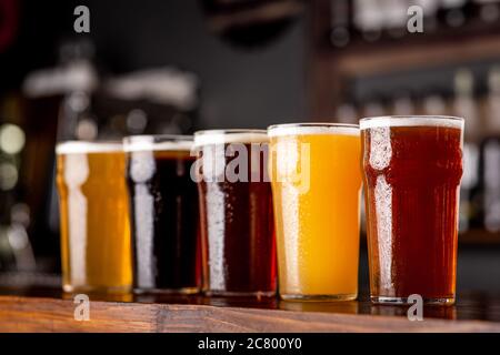 Birra artigianale e industria. Birra chiara, chiara e scura, non filtrata in bicchieri su bancone di legno Foto Stock