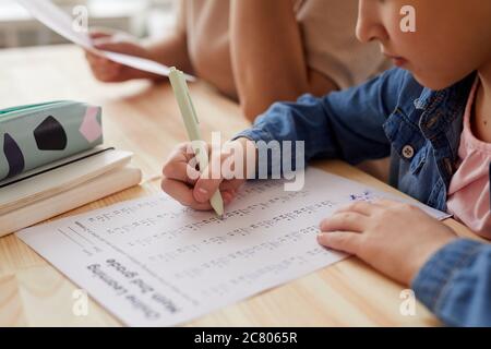 Primo piano di irriconoscibile bambina facendo test di matematica per la scuola online mentre studiano a casa, copia spazio Foto Stock