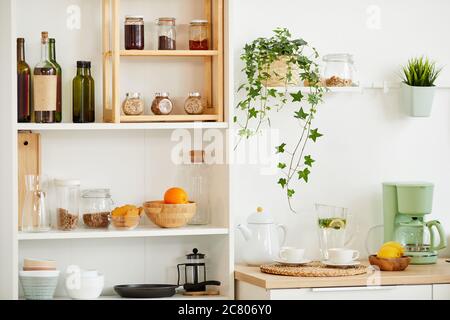 Immagine di sfondo di interni accoglienti della cucina con mensole in legno per spezie e utenci decorati con piante, spazio copia Foto Stock