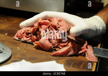 Preparazione di un sandwich di manzo al corned in stile Kosher New York una porzione pesata di manzo al cornuto viene aggiunta al sandwich Foto Stock