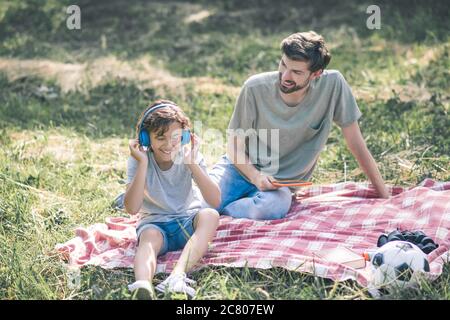 Ragazzo sorridente che gli mette le cuffie sulla testa e ascolta la musica Foto Stock