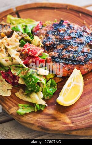 Hamburger a basso contenuto di carb (bunless) servito su una tavola rustica di legno con insalata, fuoco selettivo Foto Stock