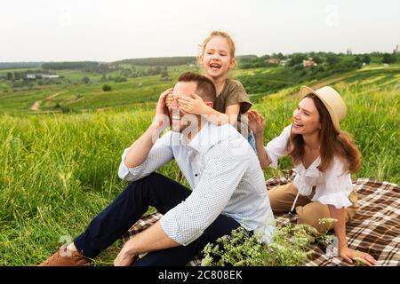 Felice giovane famiglia che gioca indovinare chi gioca su un picnic Foto Stock