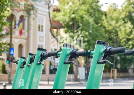 Fila di scooter elettrici blu-verde, un mezzo di trasporto alternativo più pulito e moderno nelle città. Primo piano. Foto Stock