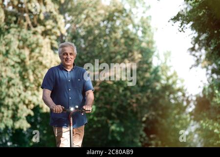 Uomo anziano che guida un calciatore elettrico nel parco Foto Stock