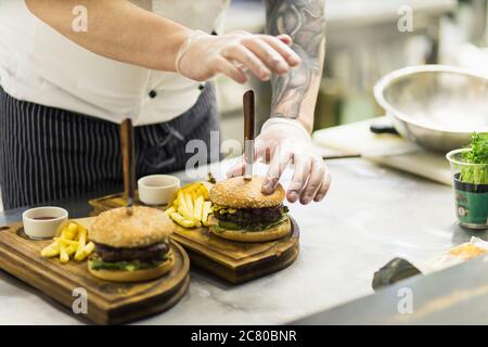 Due succulenti, deliziosi hamburger fatti in casa utilizzati per tritare il manzo. Sul tavolo di legno. Gli hamburger sono coltelli inseriti. Foto Stock