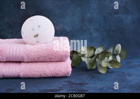 Concetto DI SPA. Bomba da bagno bianca e pila di due asciugamani rosa su sfondo chiaro. Spazio di copia per il testo. Foto Stock