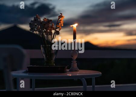 Tavolo minimalista per una cena romantica in vacanza, tavolo in legno con fiori e candele bianco. Messa a fuoco selettiva Foto Stock