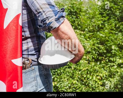 Bell'uomo con gli attrezzi, che tiene una bandiera canadese Foto Stock