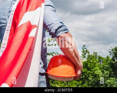 Bell'uomo con gli attrezzi, che tiene una bandiera canadese Foto Stock