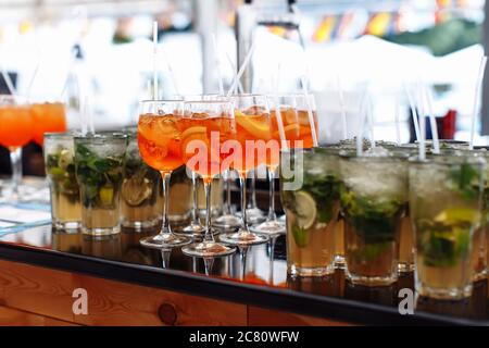 Molti bicchieri con cocktail diversi e ghiaccio al bar durante la cerimonia Foto Stock