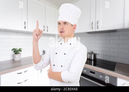 chef giovane uomo in uniforme con grande idea in cucina moderna Foto Stock