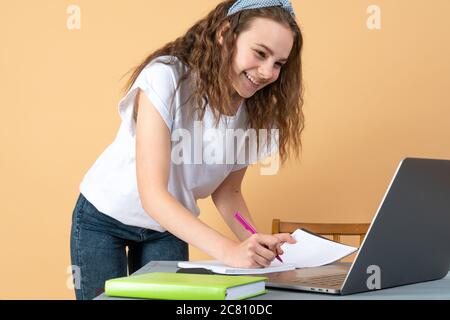 Sorridente ragazza che usa il laptop, studente che studia a casa, educazione digitale, adolescente che scrive sul web di navigazione del computer, blogger influencer che parla online Foto Stock