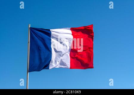 Bandiera della Francia che sventola in un cielo azzurro e limpido durante una giornata di sole Foto Stock