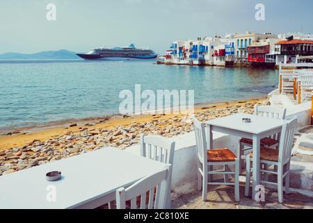 Tavolino da caffè e nave da crociera nel mare Egeo. Chora, isola di Mykonos, Grecia Foto Stock