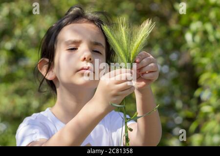 una ragazza di prety che tiene una testa di grano. La figlia contadina che tiene una testa di grano nella fattoria Foto Stock