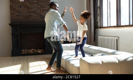 Felice padre biraciale e piccola figlia che giocano a casa Foto Stock