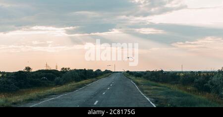 Una vecchia strada asfaltata che porta al tramonto Foto Stock