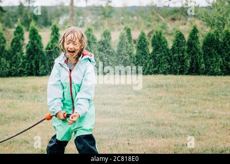 ragazza che ride mentre si gioca con acqua nel cortile a. casa Foto Stock