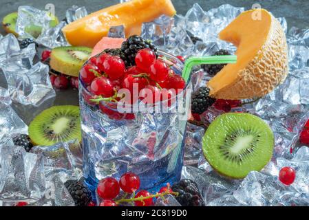 sete il bicchiere dissetante con acqua fredda e frutta fresca estiva con ghiaccio Foto Stock