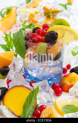 sete il bicchiere dissetante con acqua fredda e frutta fresca estiva con ghiaccio Foto Stock