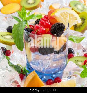 sete il bicchiere dissetante con acqua fredda e frutta fresca estiva con ghiaccio Foto Stock